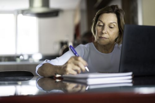 Mature woman writing in a notepad - holographic will concept